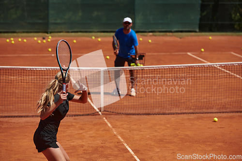 Image of A professional tennis player and her coach training on a sunny day at the tennis court. Training and preparation of a professional tennis player