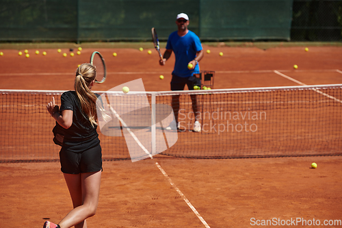 Image of A professional tennis player and her coach training on a sunny day at the tennis court. Training and preparation of a professional tennis player