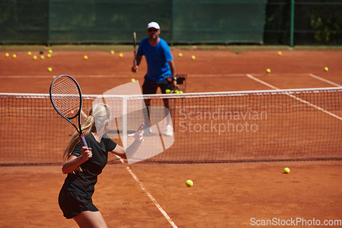 Image of A professional tennis player and her coach training on a sunny day at the tennis court. Training and preparation of a professional tennis player