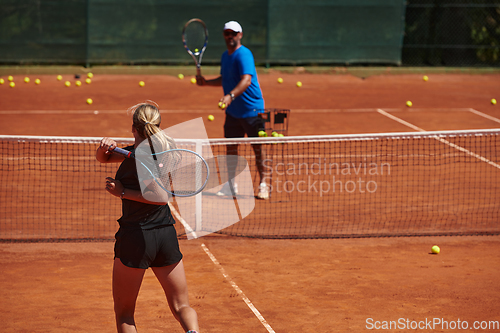 Image of A professional tennis player and her coach training on a sunny day at the tennis court. Training and preparation of a professional tennis player