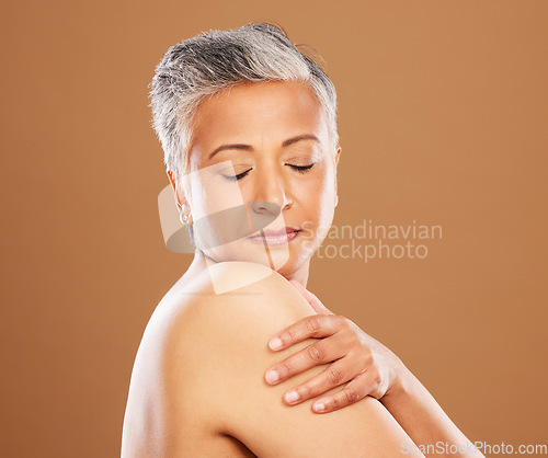 Image of Face, skincare and antiaging with a mature woman in studio on a brown background for natural skincare. Wellness, cosmetics and shoulder with a senior female posing to promote a beauty product