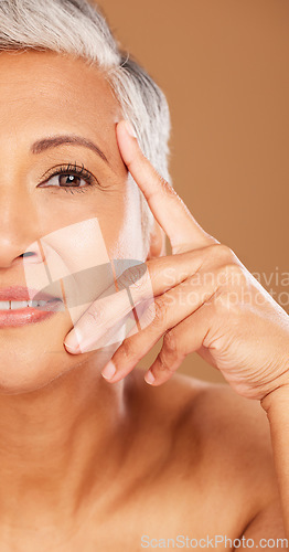 Image of Old woman, beauty and half face portrait in studio isolated on a brown background. Luxury makeup, cosmetics and retired elderly female model thinking about facial skincare, health and skin wellness.