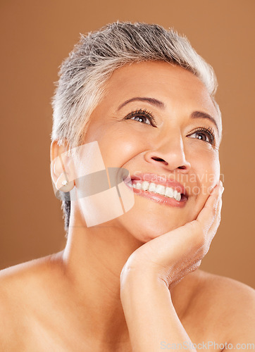 Image of Face, beauty and thinking with a senior woman in studio on a brown background for wellness or natural skincare. Idea, cosmetics or skincare with a mature female posing to promote an antiaging product