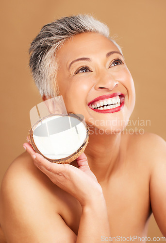 Image of Coconut, skincare, face and diet wellness keeps her happy and healthy for skin healthcare, eat healthy fruit with nutrition. Portrait of a beauty senior woman in studio against a brown background