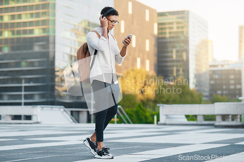 Image of Phone, music and city with a man student walking to university or college during his morning commute. Headphones, social media and 5g mobile technology with a male pupil in an urban town for a walk