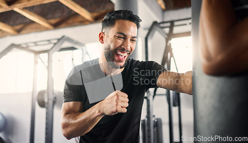 Image of Boxing gym, fitness and happy athlete boxer punching a training bag in a martial arts studio or club. Happiness of a man in a fight workout and sport exercise with a smile about healthy cardio