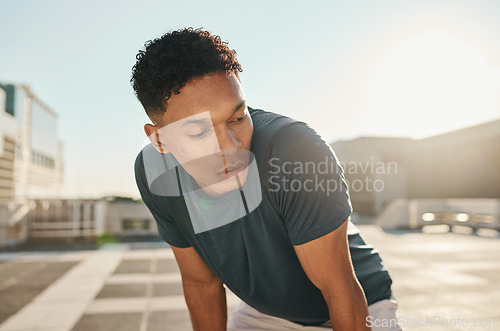 Image of Runner, fitness and tired man in a city fatigue from running exercise, cardio workout or training. Breathing, fatigue and healthy sports athlete relaxing or resting on a break from marathon training