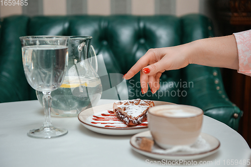 Image of Closeup photo of female hands is reaching out to cake