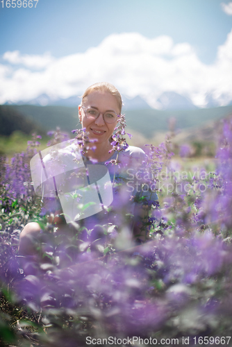 Image of Happy young woman in beautiful wild pink and purple flowers field