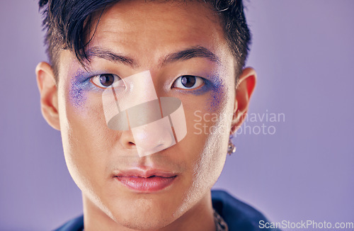 Image of Punk, artistic and man with makeup on face for metal, rock and trippy identity against a purple studio background. Expression, funky and portrait of Asian model or person in a band with cosmetics