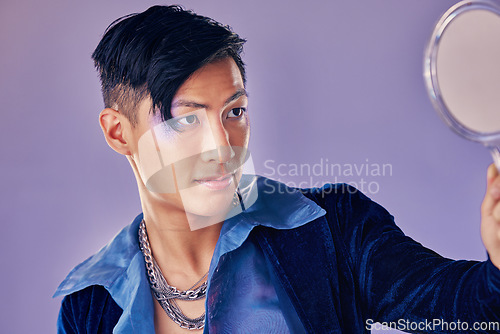 Image of Asian man with glitter makeup, mirror for creative beauty and lgbt gender performance in fantasy art. Purple background in studio, punk fashion jewellery in Seoul and proud of unique fluid identity