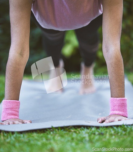 Image of Yoga, hands and mat with a woman plank closeup outdoor in a grass park for workout or training. Wellness, health and fitness with a female yogi exercising outside on grass in a garden for balance