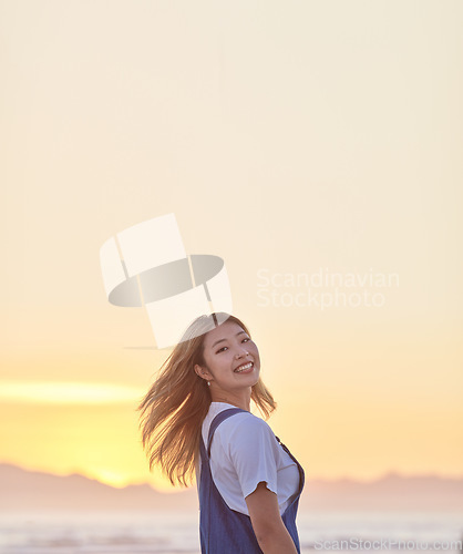 Image of Travel, sunset and smile with asian woman at beach with mockup for summer, freedom and vacation. Happy, heath and wellness with girl and relax by the ocean for peace, nature and sky on holiday