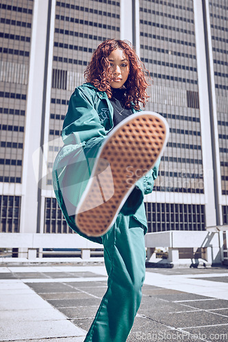Image of Fashion, city and model with a black woman on a rooftop, kicking air in contemporary clothing. Street style, portrait and confidence with an attractive young female outdoor to promote trendy style