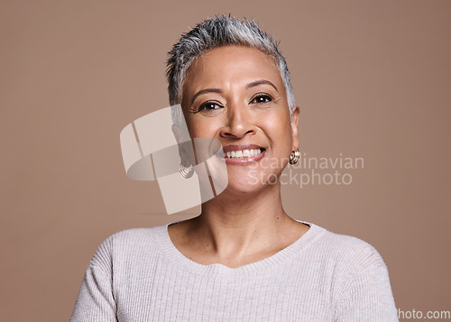 Image of Face, beauty and portrait of a senior woman with a smile standing with natural makeup in studio. Wellness, cosmetics and happy elderly lady with healthy skin posing while isolated by brown background