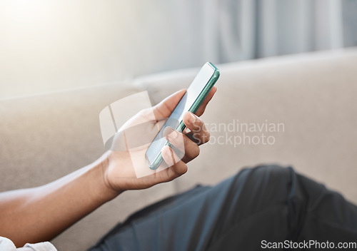 Image of Communication, online and hand typing on phone browsing internet, social media and network. Technology, communication and person relaxing on sofa at home on mobile app, texting and using smartphone