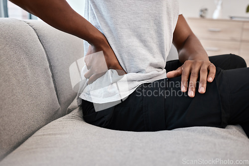 Image of hand, back pain and woman at home on the couch after injury or accident with a bad muscle. Bruise, strain and injured female with sore back on a living room sofa for rest after body emergency