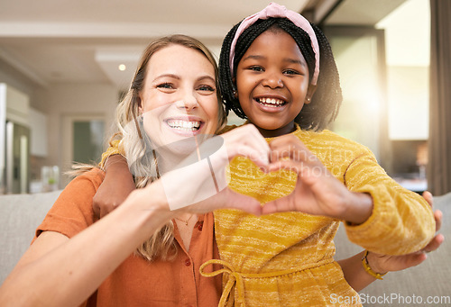 Image of Heart sign, hand and adoption with girl and mother with icon, love emoji and happy together in home. Family, smile and hand gesture, happiness and portrait on sofa in family home on the weekend