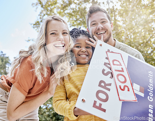 Image of Family, adoption and homeowner with a girl and foster parents holding a sold sign in their garden or yard. Portrait, diversity and love with a mother, father and daughter celebrating outdoor together