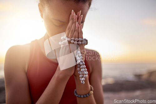 Image of Prayer, beach and hands of woman with beads for meditation, calm and peace in nature. Motivation, yoga and spiritual black woman praying by ocean for mindfulness, wellness and healthy body in morning