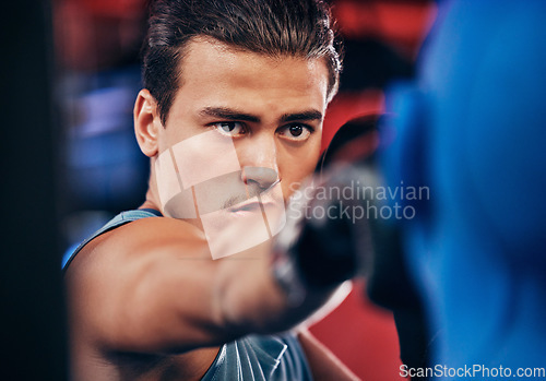 Image of Fitness, boxing and athlete training at a gym for a fighting match with a punching bag and gloves. Motivation, martial arts and man boxer or fighter practicing for MMA competition at a sports center.
