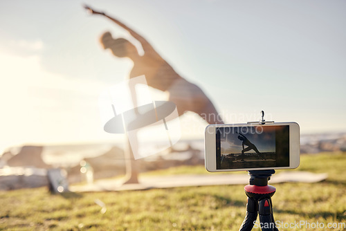 Image of Fitness, woman and yoga live stream with phone stand for social media, vlogger or exercise tutorial in nature. Female in spiritual, zen and wellness training recording sports workout on smartphone