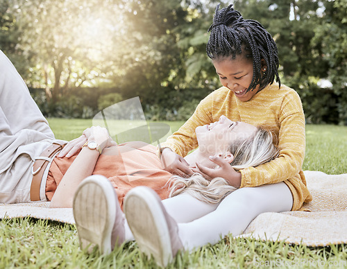 Image of Mother, picnic and happy child in a interracial family with a smile, floor hug and happiness. Summer fun, adoption and love of mom and girl on a vacation feeling relax in a garden field outdoor park