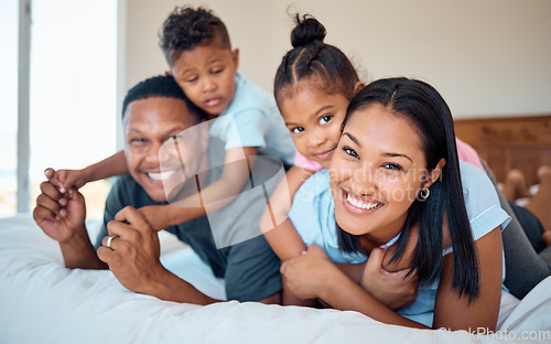 Image of Happy, smile and portrait of a family in a bedroom to relax, play and bond together at their home. Happiness, love and parents relaxing with their children while being playful on a bed at their house