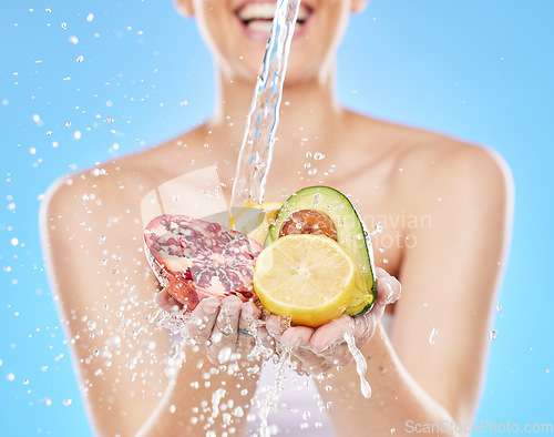 Image of Water, hands and woman with fruit in studio on blue background for nutrition, wellness and health. Girl washing, cleaning and rinse fruits and vegetable for natural, fresh and organic ingredients