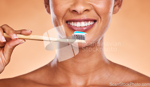 Image of Studio, dental and black woman brushing teeth on orange background. Wellness, oral health or routine of happy female model holding toothbrush and cleaning teeth for hygiene, oral care and dental care