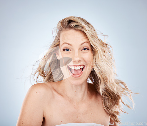 Image of Woman, excited face or expression and blonde hair in motion on gray studio background in frizz free wavy hairstyle. Portrait, happy smile or wow beauty model and healthy hair care or grooming routine