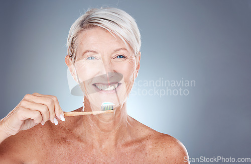 Image of Smile, dental and senior woman brushing teeth for healthcare, wellness and breath against a grey mockup studio background. Happy, healthy and portrait of an elderly model with toothpaste for breath