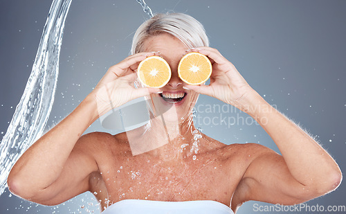 Image of Water splash, fruit and senior skincare of a woman holding orange for vitamin c and skin glow. Beauty, clean detox and cosmetic health wellness of a model happy about shower, diet and nutrition