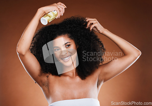 Image of Hair care, afro and spray with wellness, cosmetic and happy smile against a brown studio background with mockup. Happiness, health and care for curls with beauty, natural or luxury cosmetics product