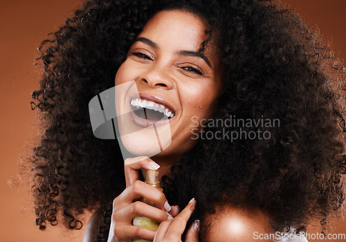 Image of Hair care, spray and portrait of a black woman with an afro doing a routine with wellness product. Health, cosmetics and happy African model with hairspray for her natural hair by a brown background.