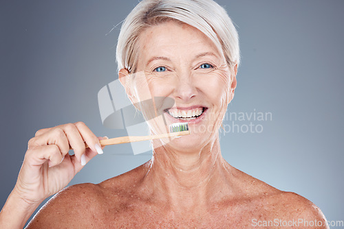 Image of Dental, studio and senior woman brushing teeth on a gray background. Oral health, wellness and routine of elderly female from Canada holding toothbrush and cleaning teeth for hygiene and oral care
