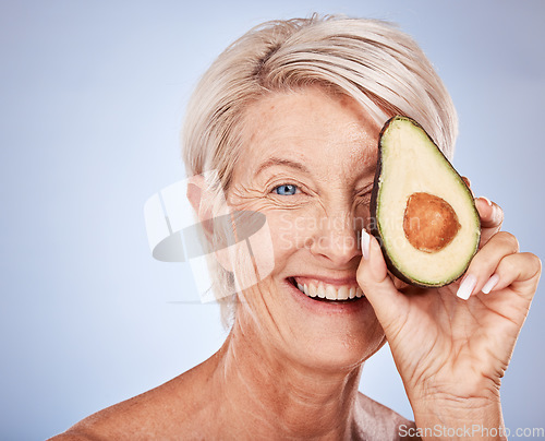 Image of Face, skincare and avocado with a senior woman in studio on a gray background to promote antiaging antioxidants. Portrait, cosmetics and natural treatment with a mature female posing for wellness