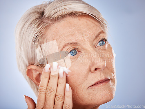 Image of Mature woman, cream and apply face cream or lotion for wrinkle anti aging on a grey studio background. Spf, suncream with a senior female apply sunscreen for health, wellness and protection