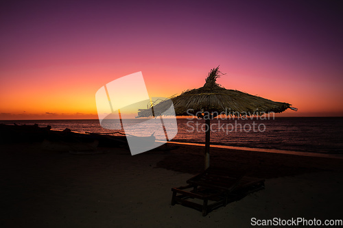 Image of Vibrant red sky at sunset on Anakao beach in Madagascar, with a tropical parasol and sun lounger
