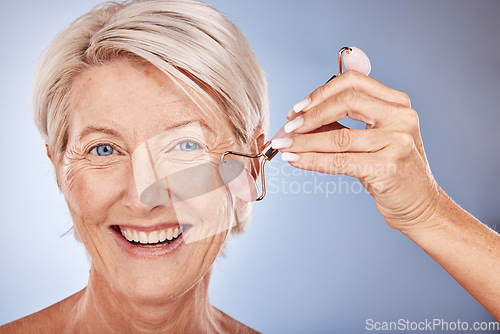 Image of Skincare, face roller and senior woman with a beauty, natural and fresh skin routine in a studio. Cosmetics, face and portrait of elderly lady with a facial tool doing a cosmetic anti aging treatment