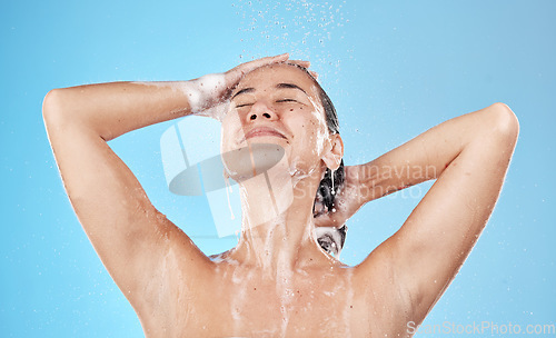 Image of Beauty, hair and woman in shower happy on blue background, haircare and hygiene routine in the morning. Model in water with shampoo foam, cleaning hair with running water for clean fresh lifestyle.