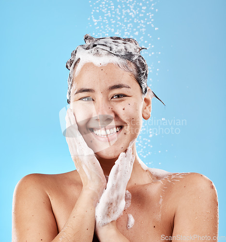 Image of Woman, shower and for hygiene being clean and with smile for wellness against blue studio background. Portrait, water and Asian female or girl happy, with shampoo and skincare for health or body care