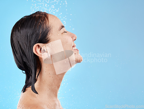 Image of Asian woman, shower and water for cleaning, smile and happy in blue studio mockup background. Model, clean and showering face, body and hygiene, skincare or cosmetic beauty in bathroom with happiness