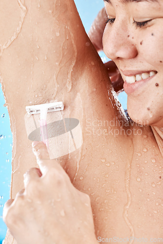Image of Woman, shower and shaving armpit skin for cleaning, skincare or hygiene with smile against blue background. Model, bathroom and shave body, hair or underarm for self care, beauty or cosmetics in home