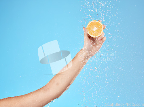 Image of Lemon, water and hand of woman with fruit for health, beauty and wellness against blue mockup studio background. Cleansing, nutrition and person with vitamin c while showering for a detox with space