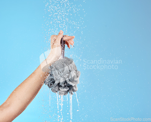 Image of Shower, water and hands with a loofah for luxury wellness, cleaning and grooming against blue studio background. Health, cosmetic and woman with product for body care and treatment with mockup space