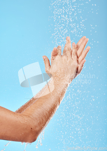 Image of Woman, water splash and washing hands on blue background in studio for bacteria safety, hygiene maintenance or morning grooming. Zoom, model or skincare shower cleaning in wet healthcare or wellness