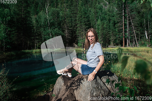 Image of Woman resting at mountain lake in summer