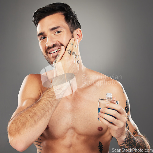 Image of Man, aftershave and skincare portrait for face and beard on a grey studio background for wellness and beauty. Skin care, cologne and man apply product to face for grooming, clean facial hair