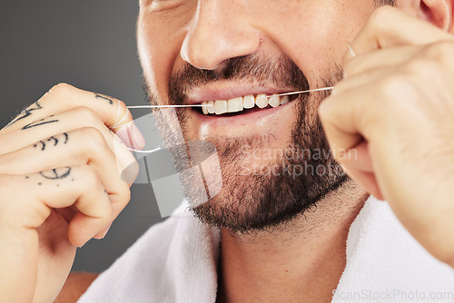 Image of Floss, dental hygiene and man cleaning teeth, for wellness and against grey studio background. Oral health, healthy male and thin filaments string for fresh breath, remove plaque and mouth healthcare